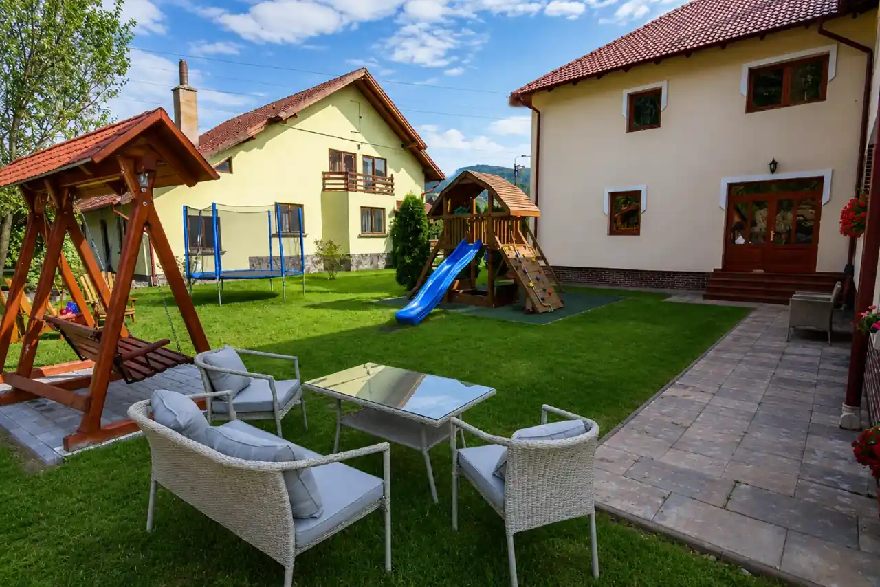 Gazon cu loc de joacă și mobilier de grădină lângă pensiune